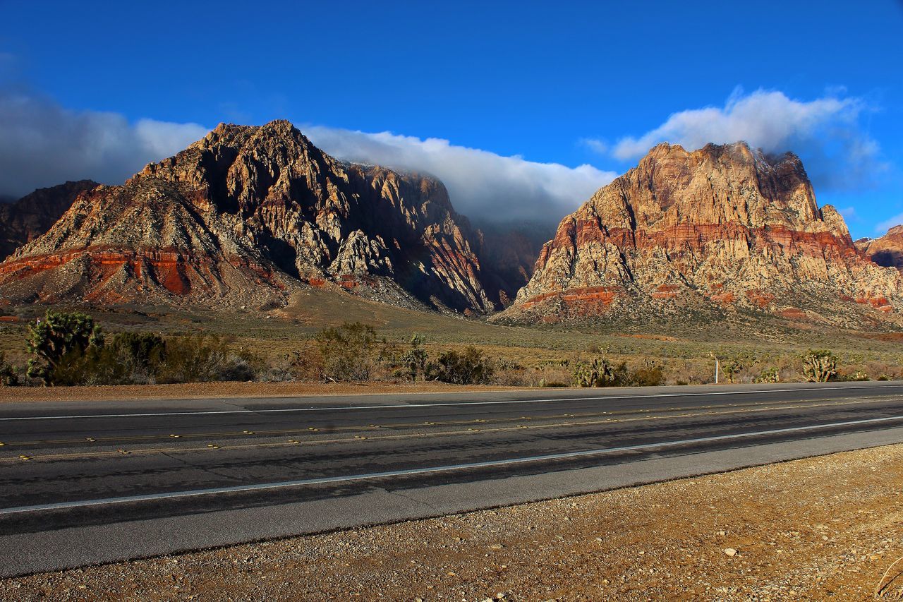 mountain, sky, mountain range, scenics, cloud - sky, beauty in nature, tranquility, tranquil scene, nature, road, blue, cloud, rock - object, landscape, rock formation, rocky mountains, non-urban scene, day, outdoors, no people