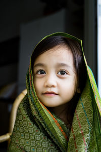 Portrait of cute asian toddler, kid, girl wearing traditional songket shawl.