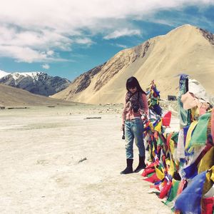 Woman looking down while standing by prayer flags