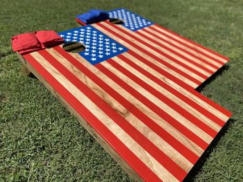 Set of hand-painted american flag cornhole boards and bags, sitting on the lawn.