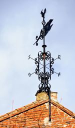 Low angle view of weather vane against sky