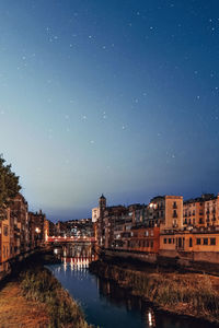 River by illuminated city against sky at night