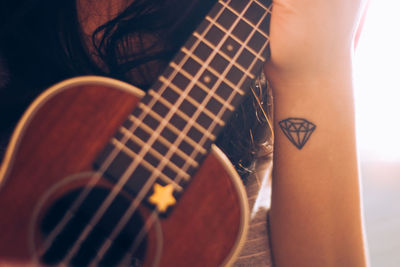 Midsection of woman playing ukulele