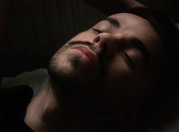 Close-up of man sleeping against black background