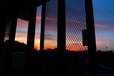 Silhouette fence against orange sky