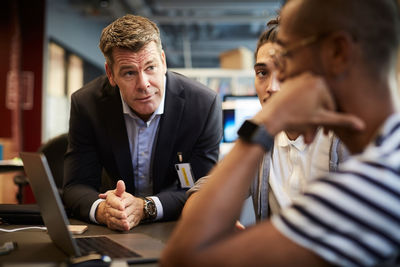 Bank manager looking at male entrepreneur at desk during meeting in creative office