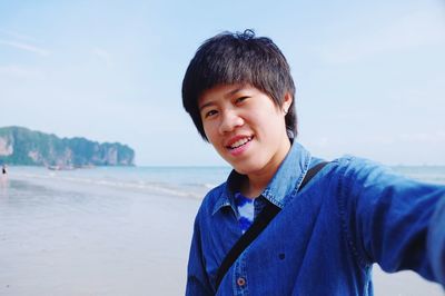 Close-up portrait of smiling man standing on sea against sky