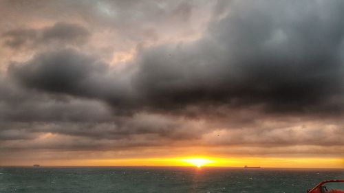 Scenic view of sea against dramatic sky during sunset