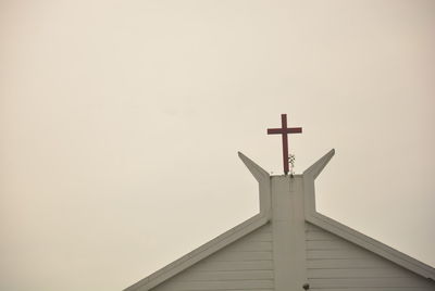 Low angle view of cross on building against sky