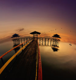 Silhouette pier over sea against sky during sunset