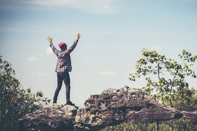 Man standing on rock against sky