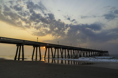 Pier over sea against sky during sunset