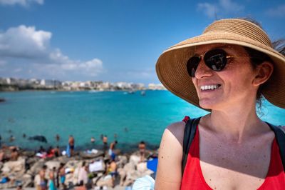 Portrait of young woman looking at beach against sky