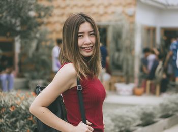 Portrait of smiling young woman standing in city