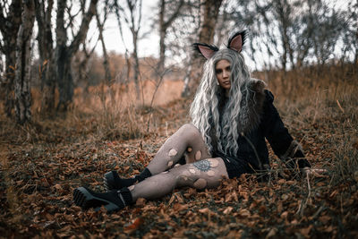 Young woman standing against tree during autumn