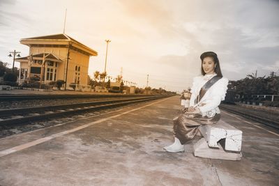 Portrait of woman in traditional clothing sitting on railroad station platform