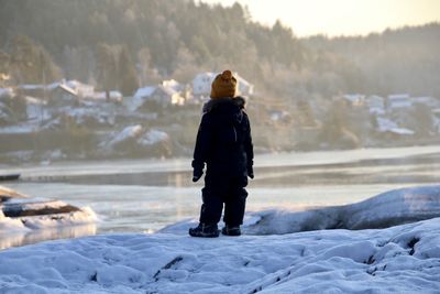 Rear view of woman standing on snow covered land