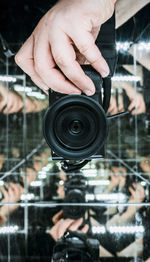 Cropped hand of person holding camera with reflection in mirrors