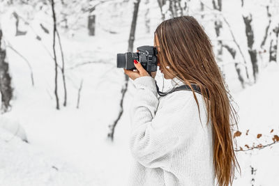 Rear view of woman photographing during winter