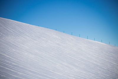 Low angle view of snow covered landscape against blue sky