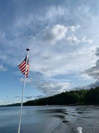 Red flag by river against sky