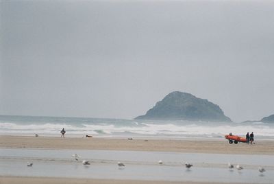 Sea and people at beach against sky