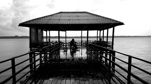 People on pier by sea against sky