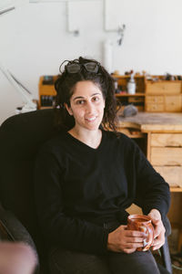 Smiling women with glasses sits with mug in home workspace