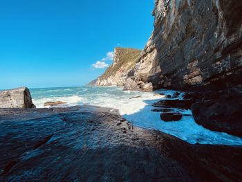 Rock formations on shore against blue sky - byrons grotto