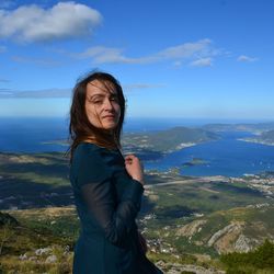 Beautiful young woman standing on mountain against sea