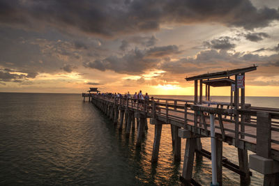 Pier over sea against sky during sunset