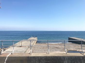 Scenic view of swimming pool by sea against clear sky