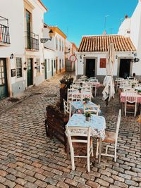 Chairs and tables on street amidst buildings in town