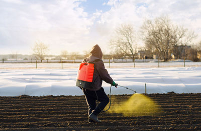 The farmer treats the field from weeds and grass for growing potatoes. use chemicals in agriculture