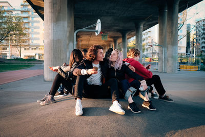 Friends looking up while standing below bridge on sunny day