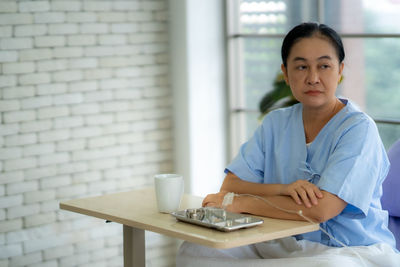 Portrait of young woman using mobile phone while sitting on table