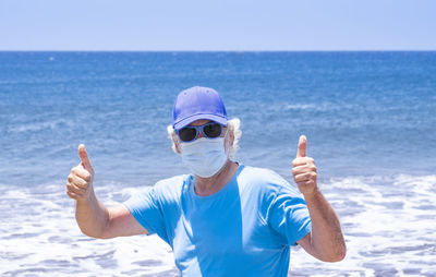 Portrait of senior man standing by sea against sky