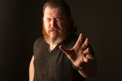 Portrait of man standing against black background