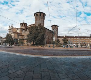 Empty road by buildings in city against sky