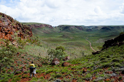 Man walking on mountain against cloudy sky