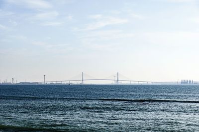 Suspension bridge over sea against sky