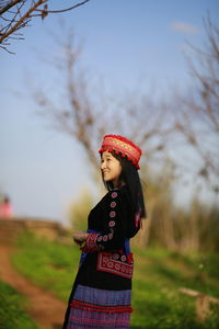Woman looking away while standing on field against sky