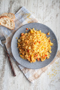 Bulgur with stewed vegetables in a plate on a light wooden background. top view with space for text.