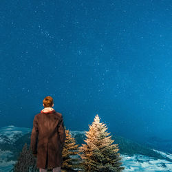 Rear view of man standing in snow against sky