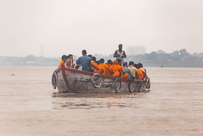 People on boat in sea against clear sky