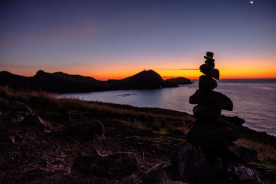 Stack of rocks on shore during sunset