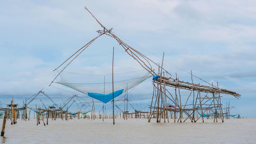 Cranes on beach against sky