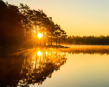 A tranquil, idyllic landscape of a swedish lake at sunrise with mist and sunlight 