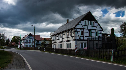 Road by houses against sky in city