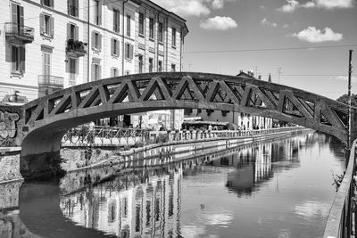 Bridge over river by buildings against sky